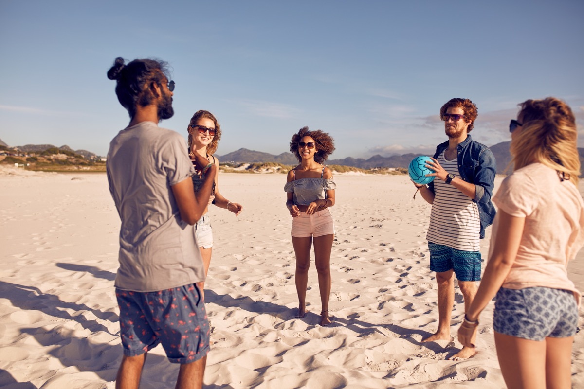 group of friends asking each other dirty would you rather questions on the beach