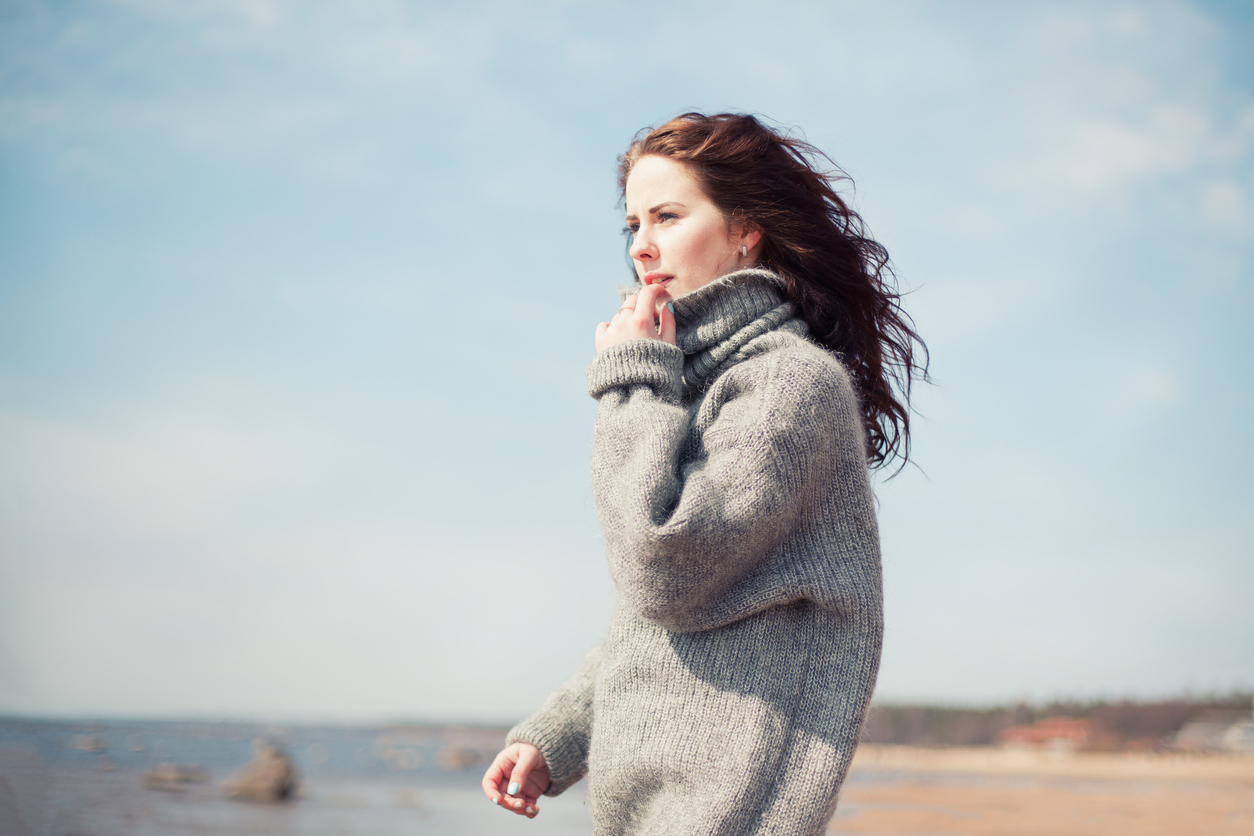 Attractive woman wearing a warm cardigan at the cold beach