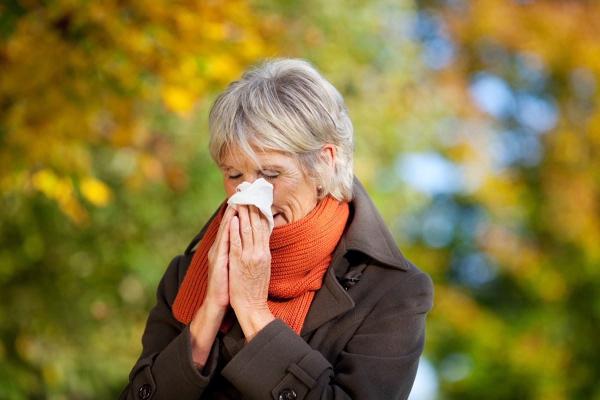 Senior woman in jacket suffering from cold in park