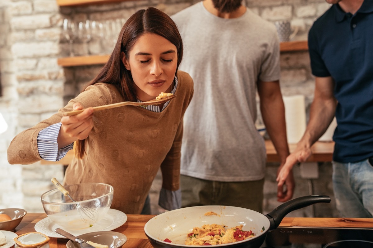 Woman tasting food she is making before seasoning