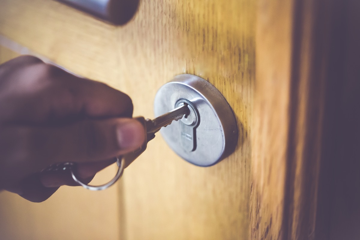 Man opening the door to his home with his steel key.