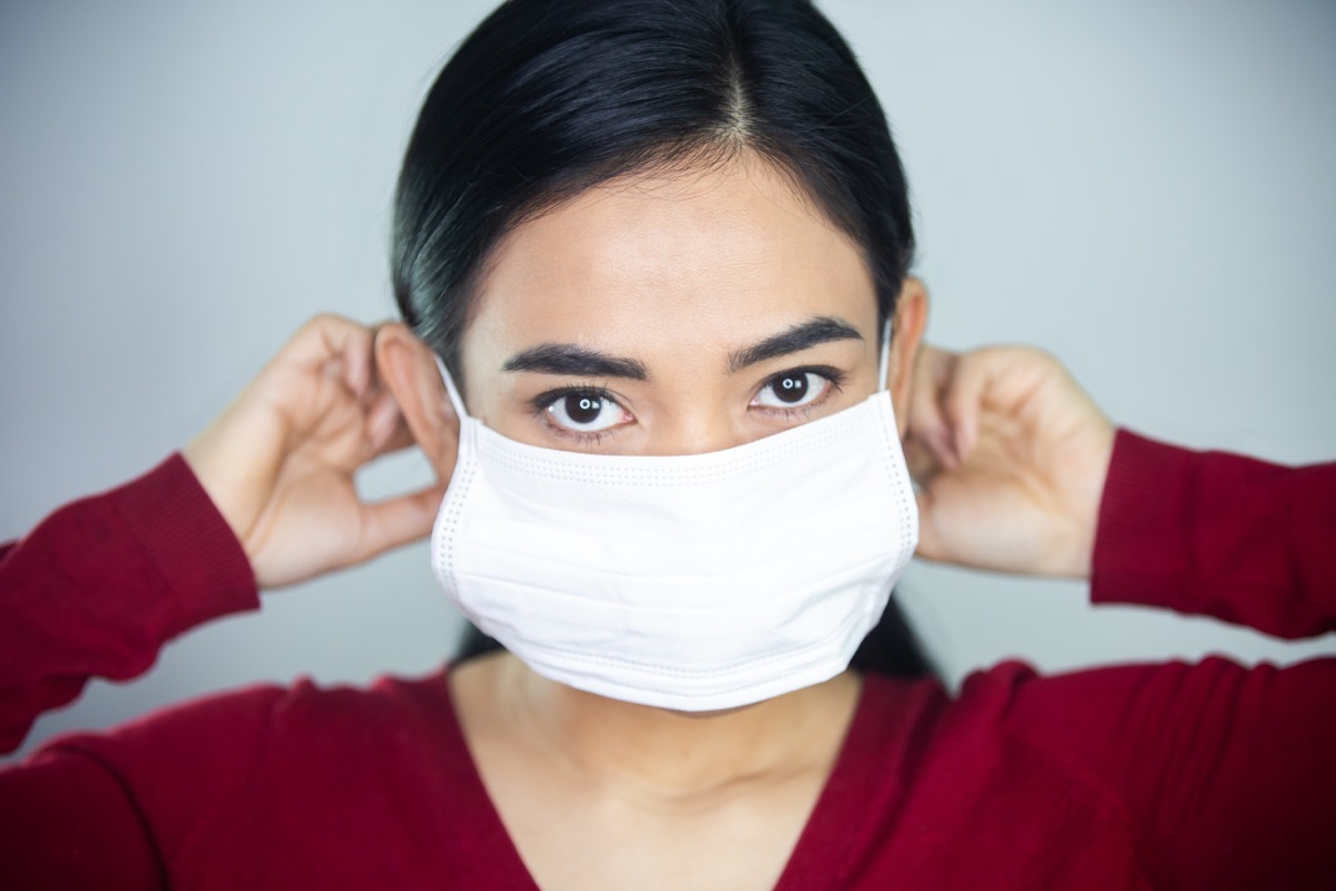 Woman making sure mask is comfortable before wearing