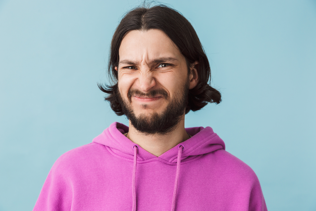 Portrait of a disgusted young bearded man wearing hoodie