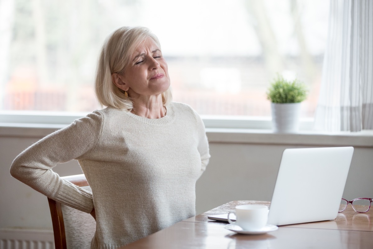 Upset mature middle aged woman feels back pain massaging aching muscles