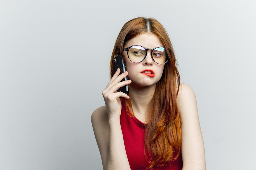 woman sucking in her lip having an uncomfortable conversation on the phone