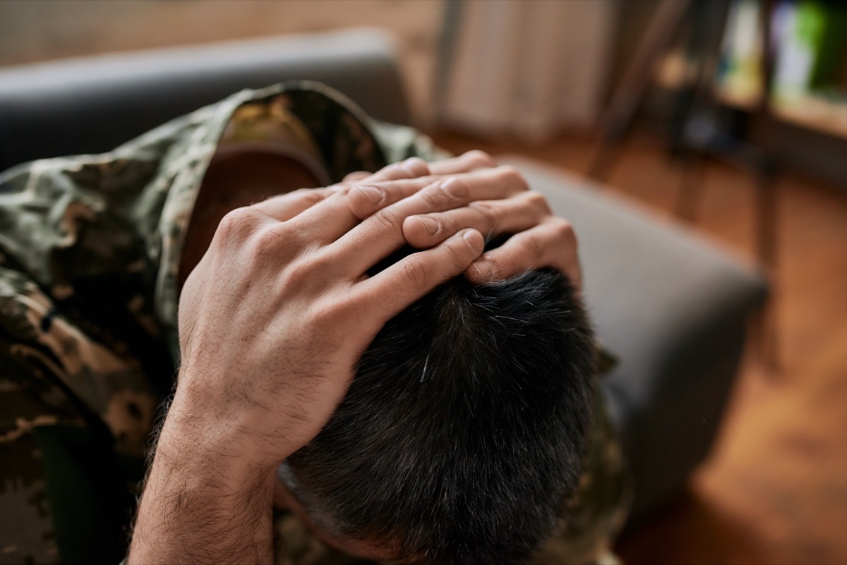 military man sitting down with his head in his hands