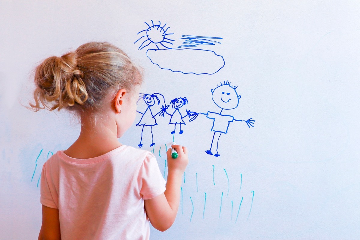 Young girl drawing picture on white board