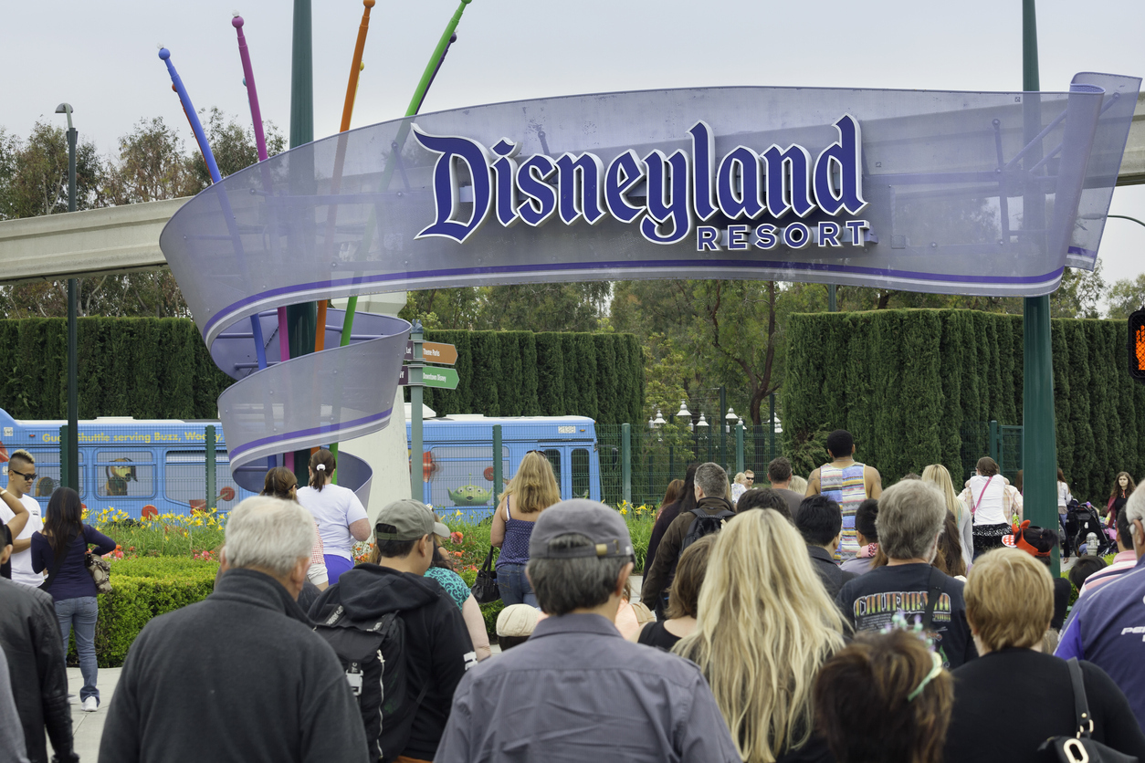 A crowd of people walking in through the entrance to Disneyland park