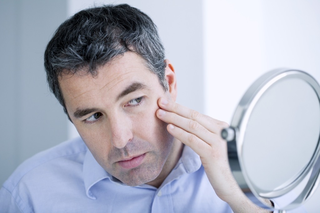 man looking in the mirror for wrinkles turning 40