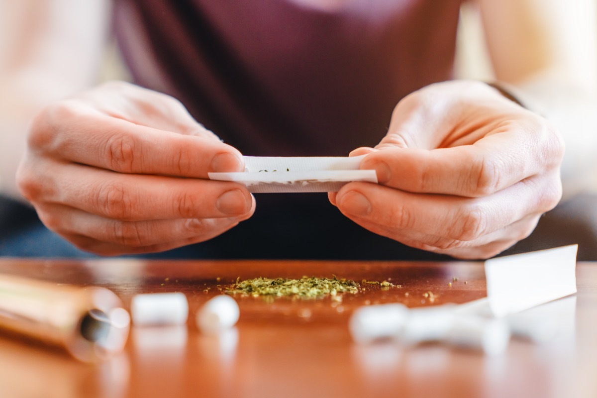 Young man making marijuana joint.