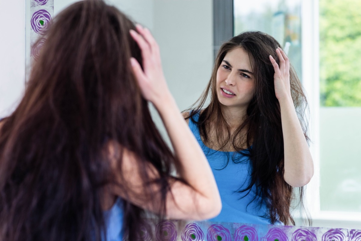 Girl looking at her hair in the mirror