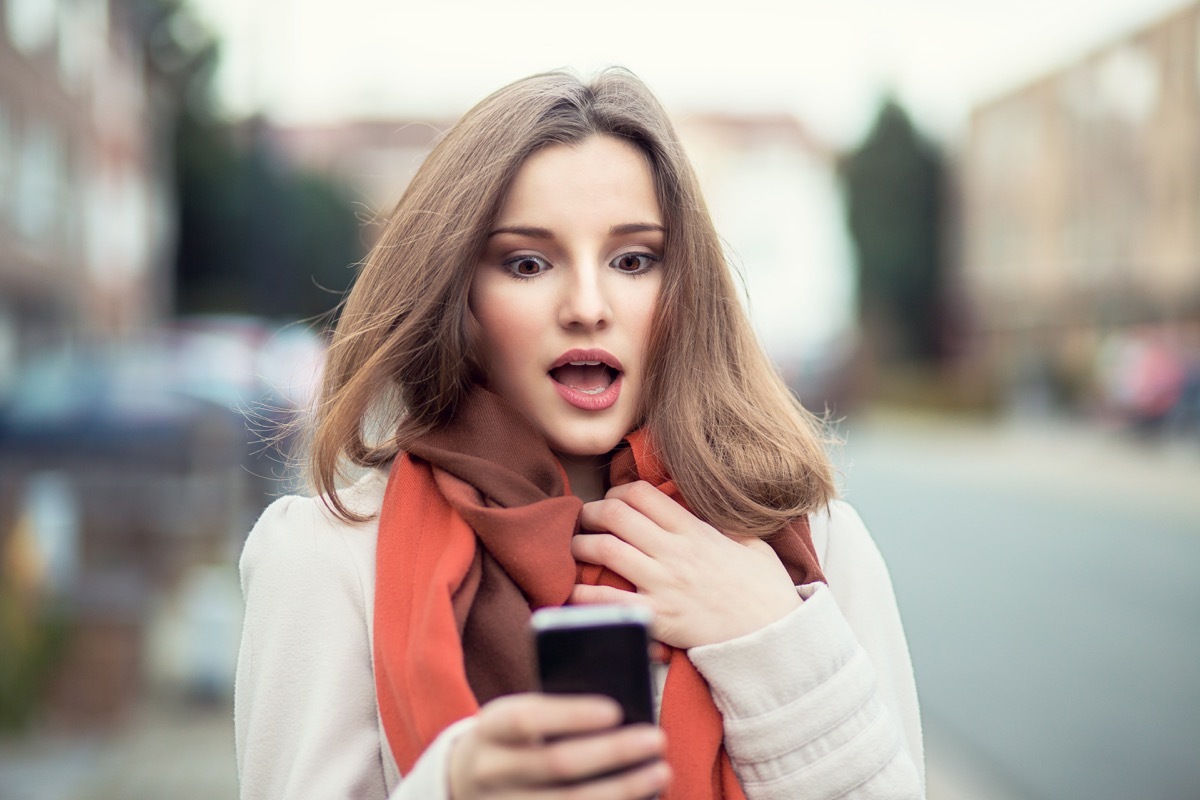 woman looking shocked at her phone