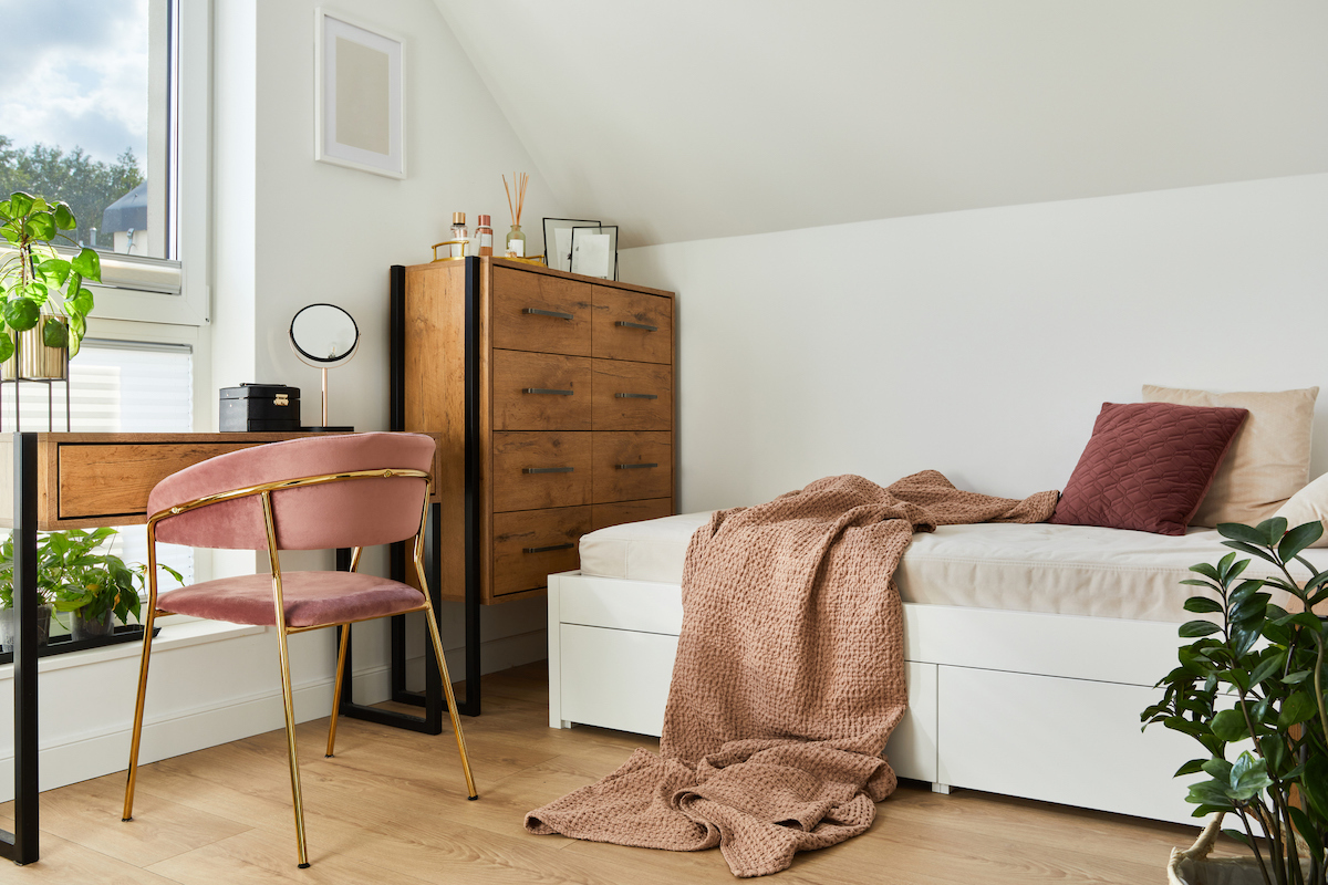 A bedroom slash home office with natural wood and mauve accents