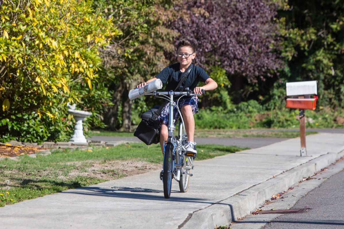 boy carrying newspaper on bicycle, paper route