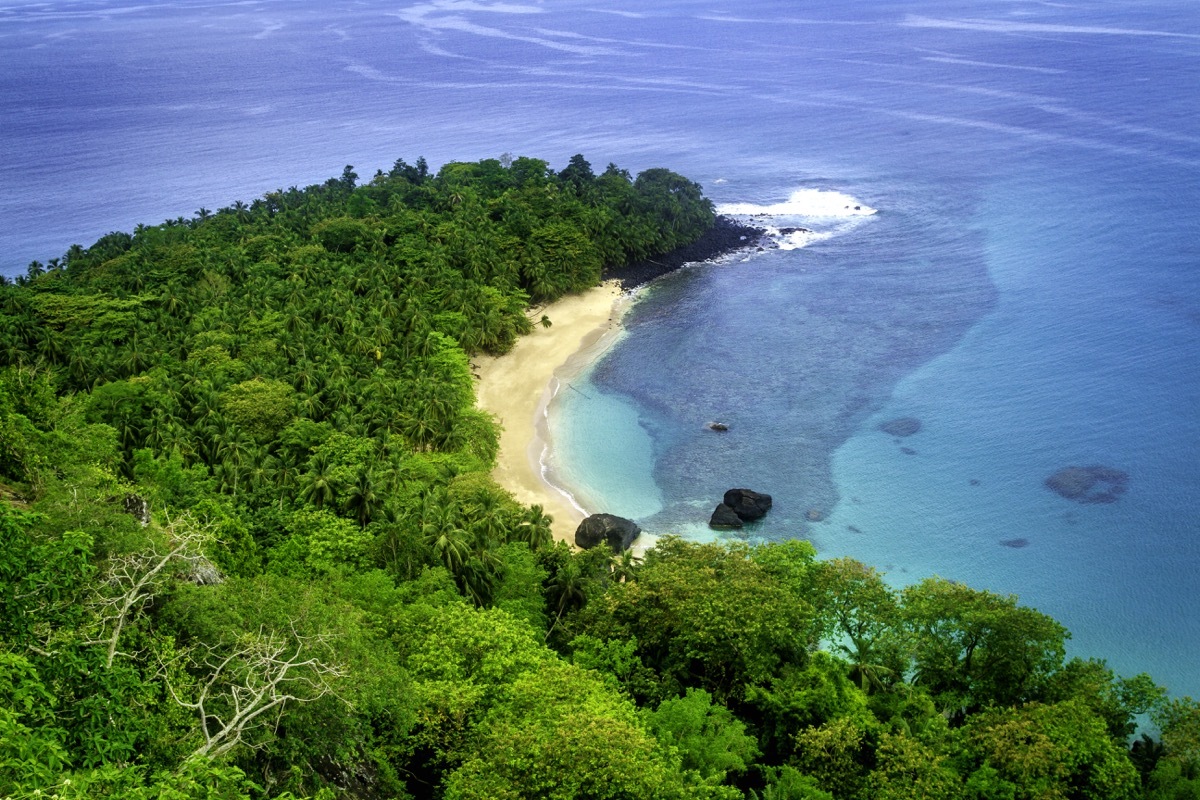 The most famous beach in Principe Island, the tiny island of S√£o Tom√© and Principe, on the west coast of Africa. This is perfect for swimming, with white sand curving in a banana shape around turquoise waters