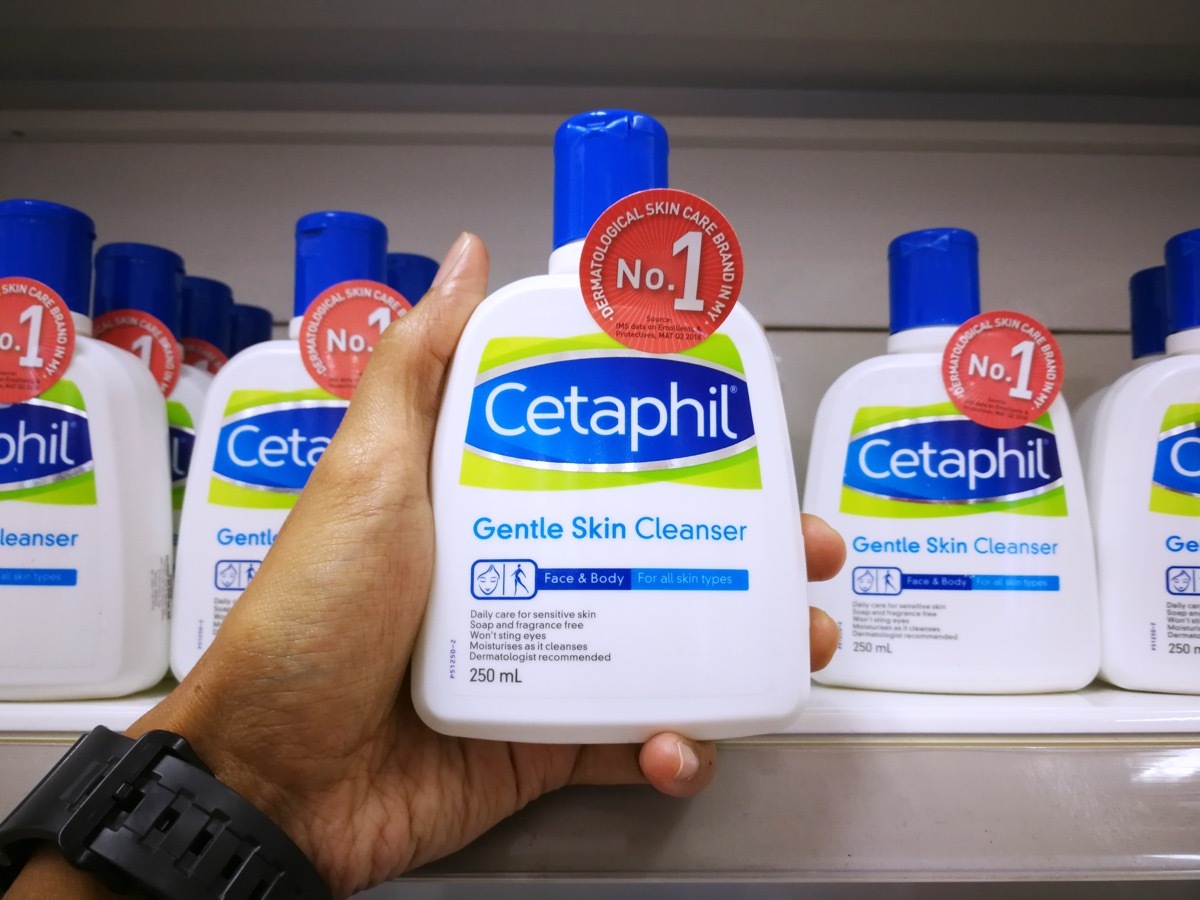 man holding a cetaphil bottle off the shelf