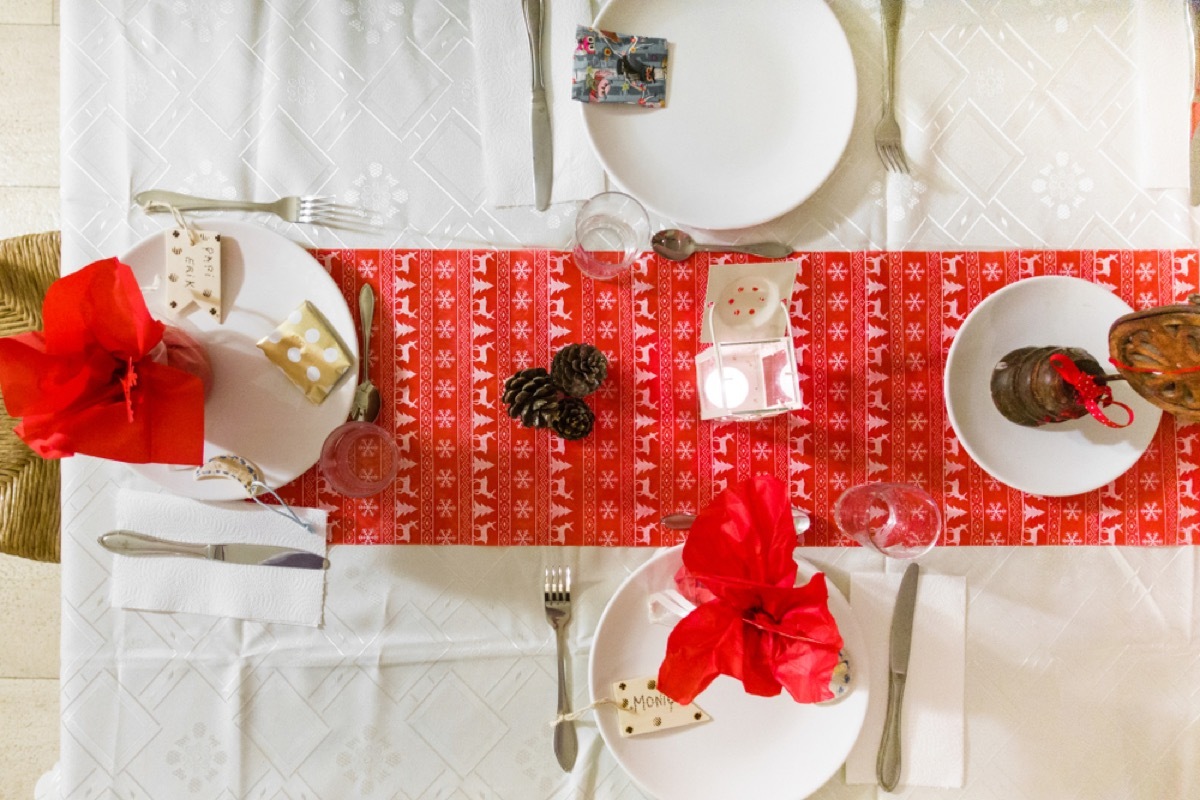 dining table with white plates and red holiday runner