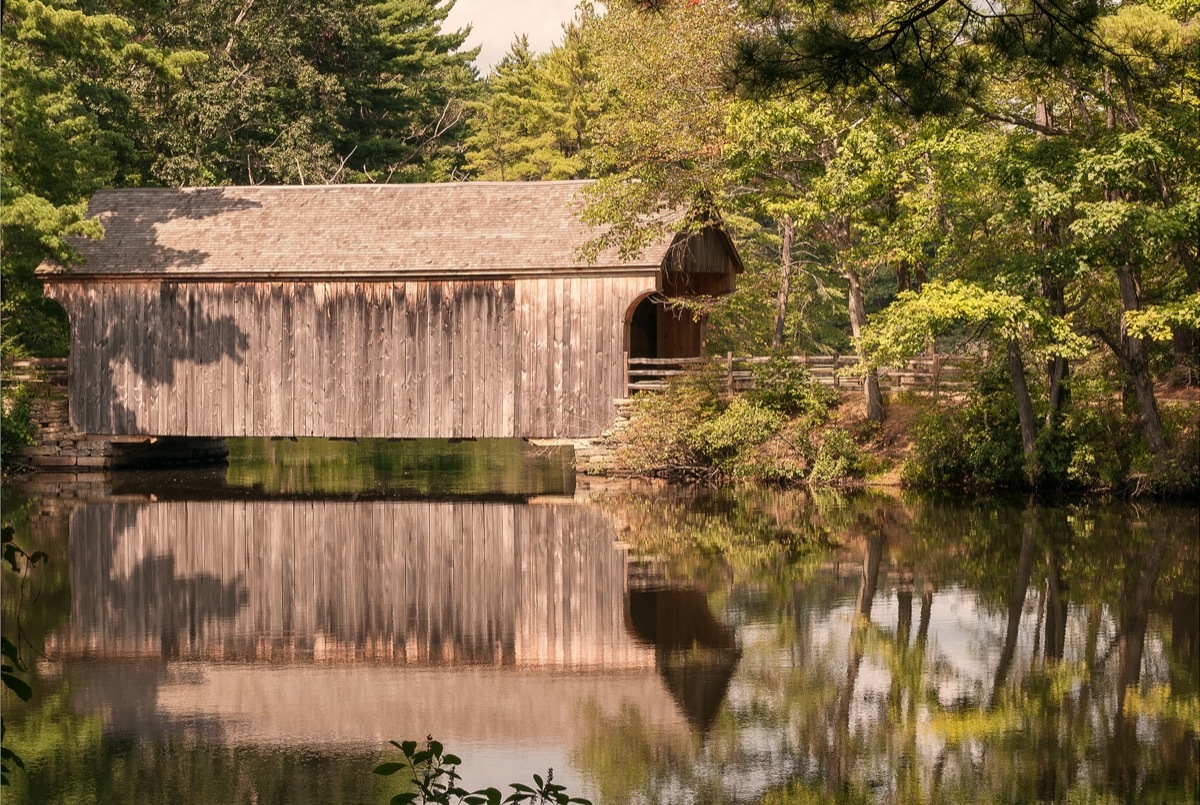 covered wooden bridge reflecting in water