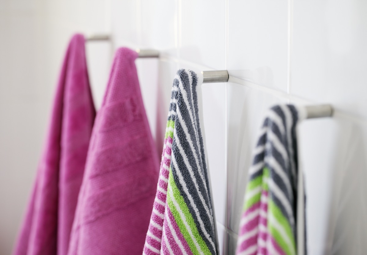 pink bath towels and striped bath towels on hooks