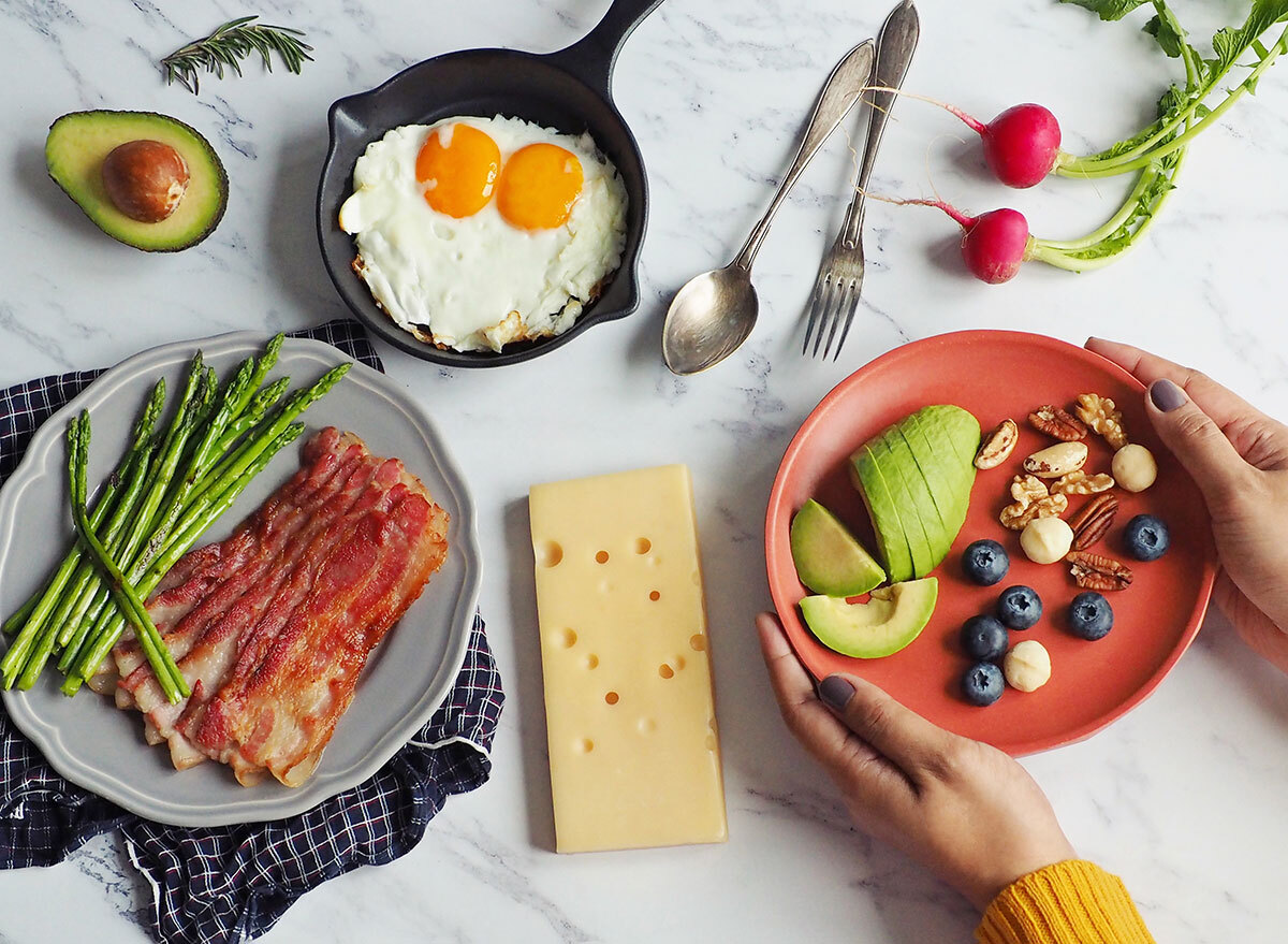 Woman holding plate of keto foods at a table