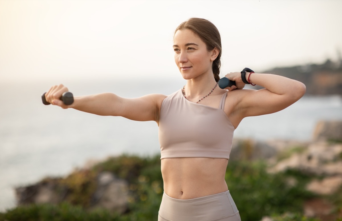 Woman working out with light dumbells outdoors