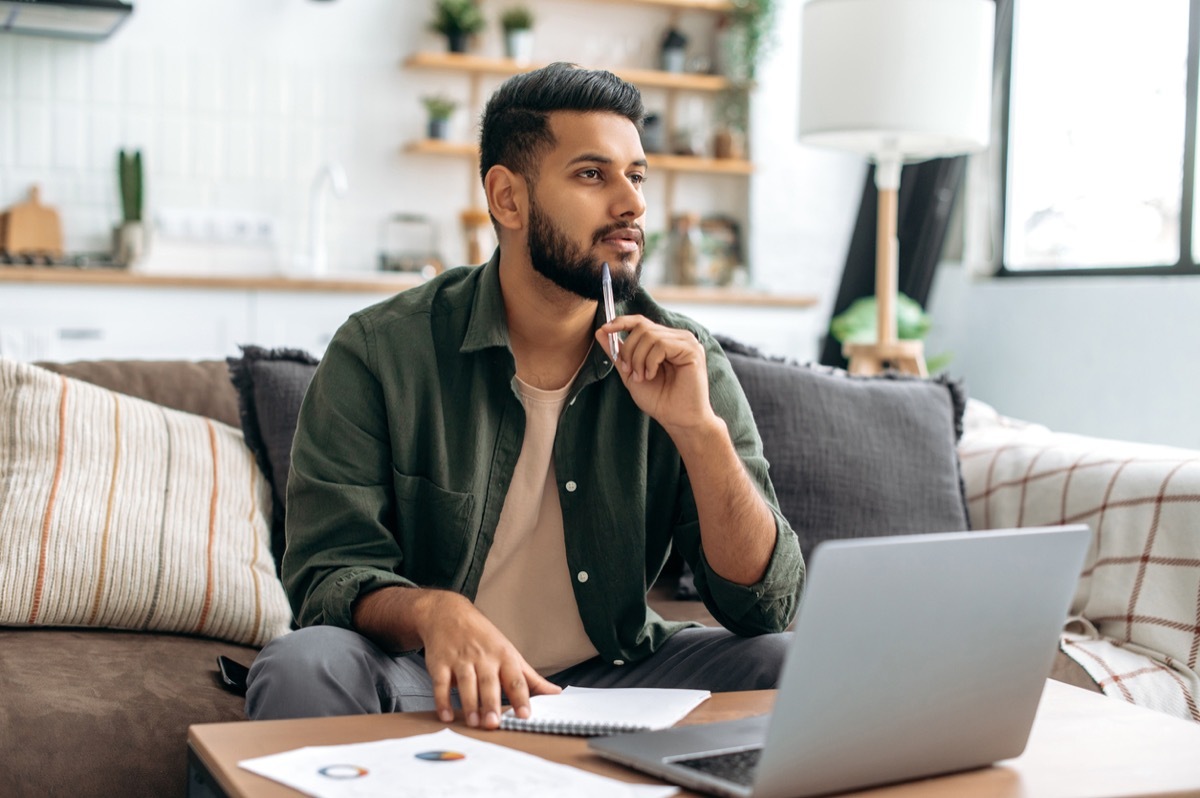 Pensive clever man using laptop