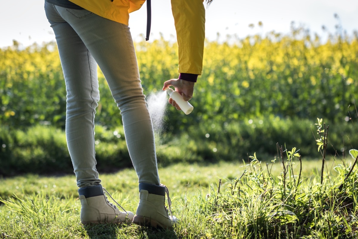 Tourist spraying insect repellent on her legs and boots