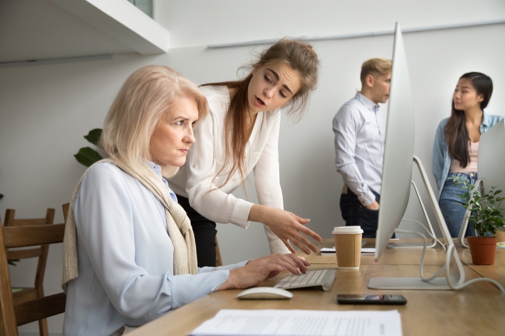 woman looking angry at older coworker on computer