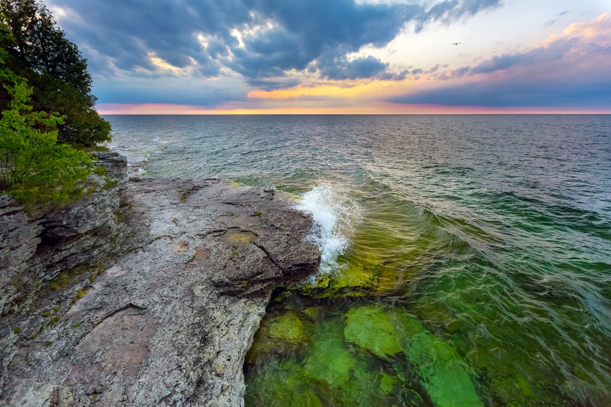 waves breaking next to trees and rocks on the coast of Wisconsin's Cave Point at dawn