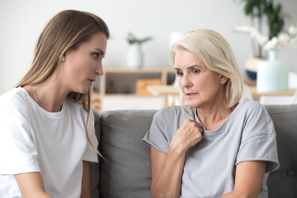 young woman talks to senior woman, possibly mother and daughter, on couch