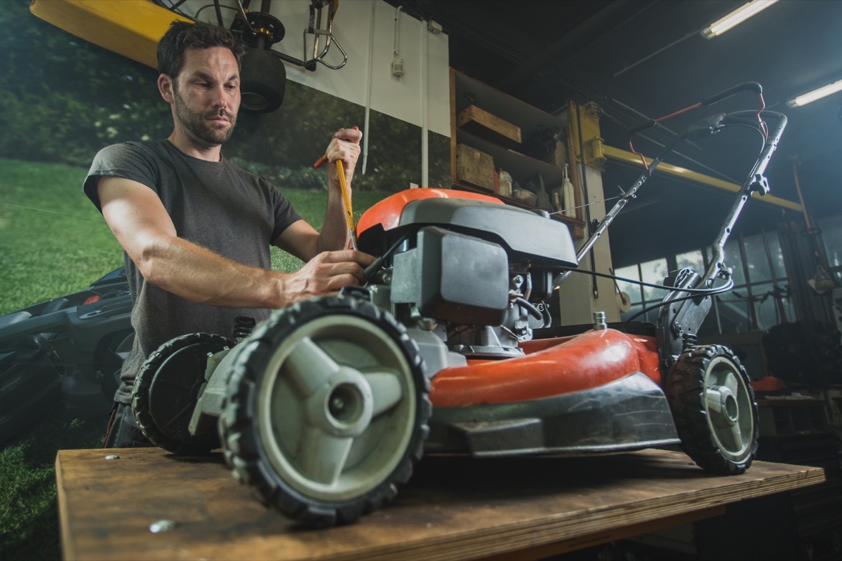 man fixing lawn mower in garage