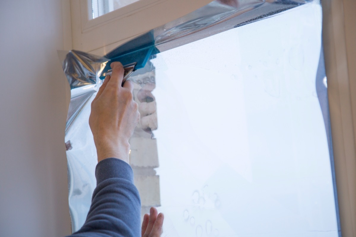 man installing reflective window film