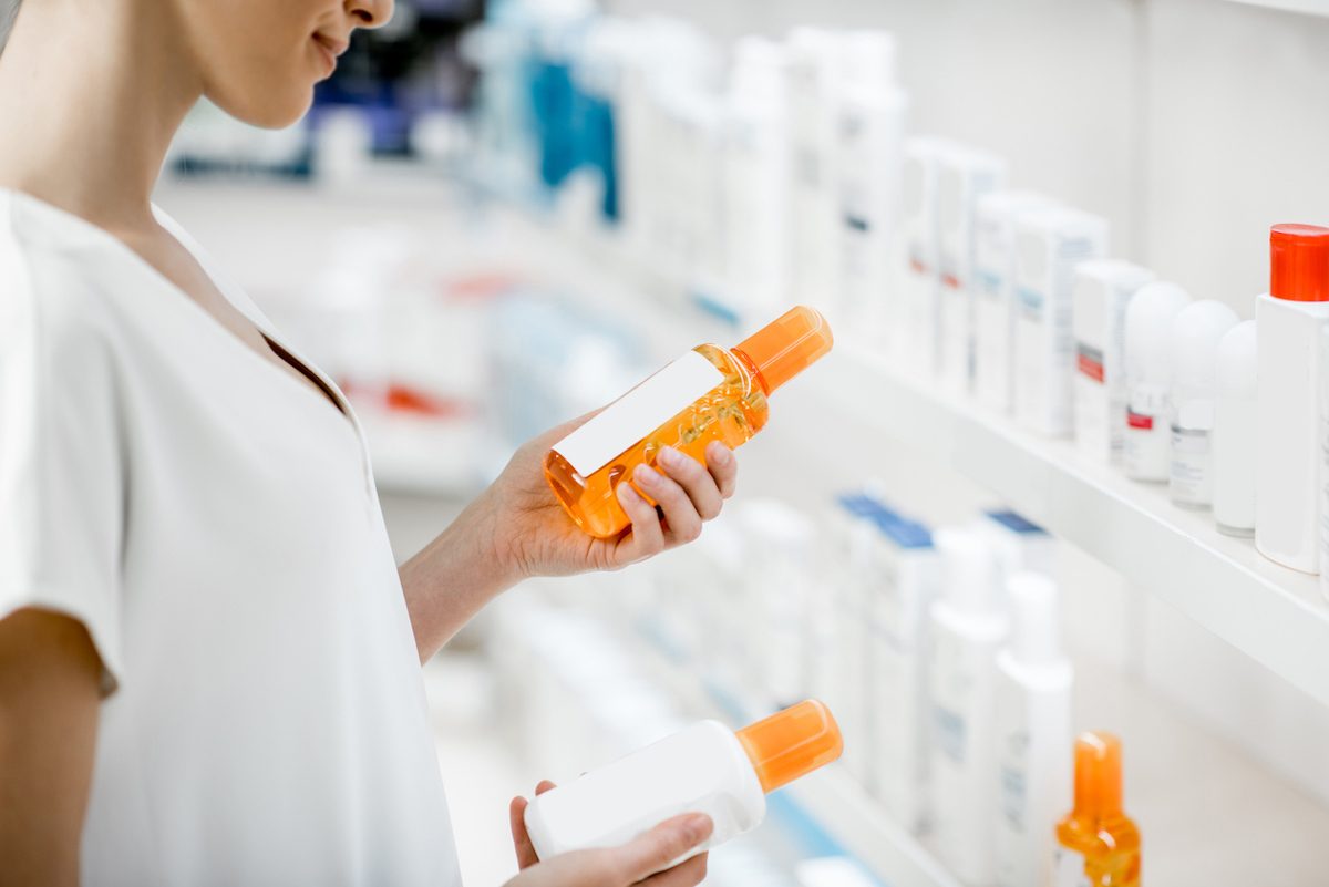 A woman holding two bottles of skincare products from the shelf at a store