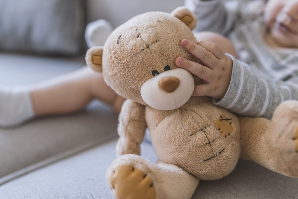 baby hands holding a teddy bear. Baby in bed, holding a teddy bear