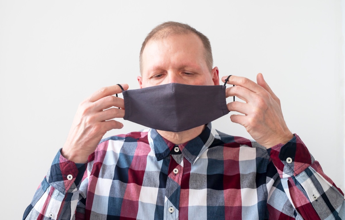 older white man putting on face mask