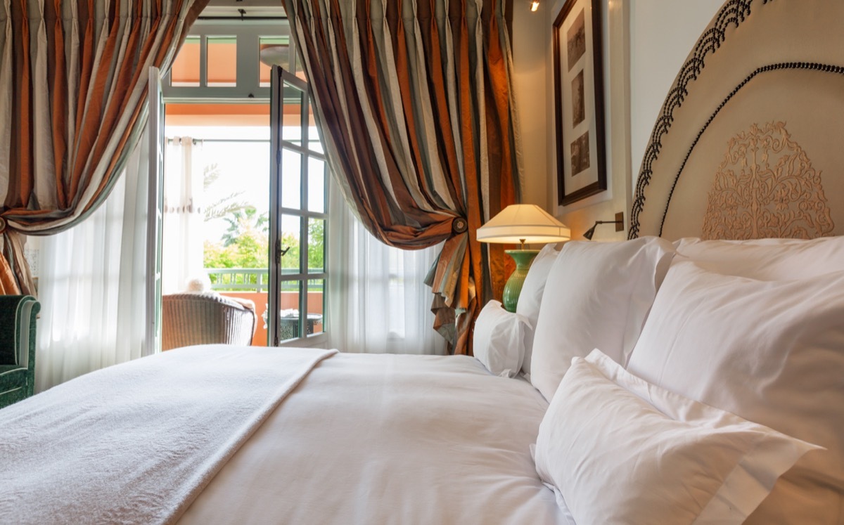 Luxury bedroom that opens with French doors onto a terrace. King bed with white linens and pillows.