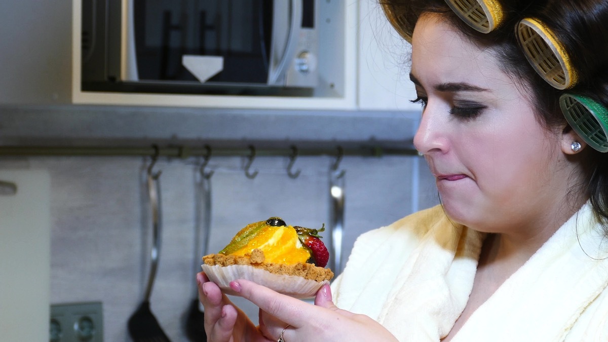 Woman eating dessert at night feeling guilty and ashamed