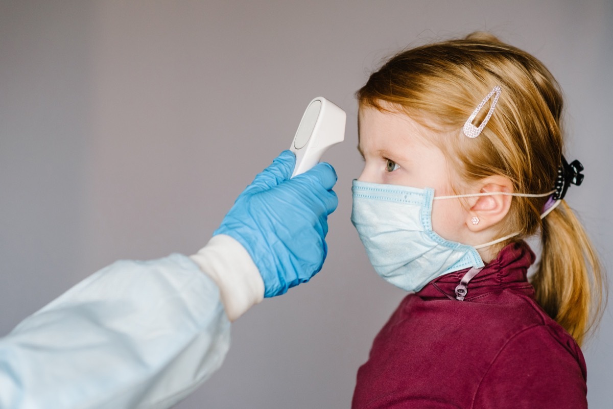 doctor or nurse with gloved hands checking little girl's temperature