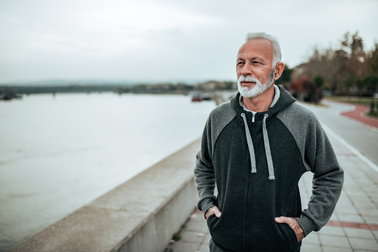 A senior man walking alongside a river