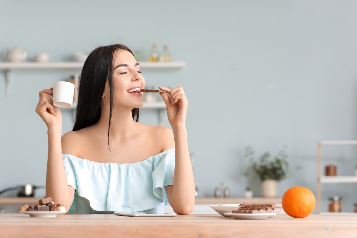 Woman eating chocolate in the morning with coffee