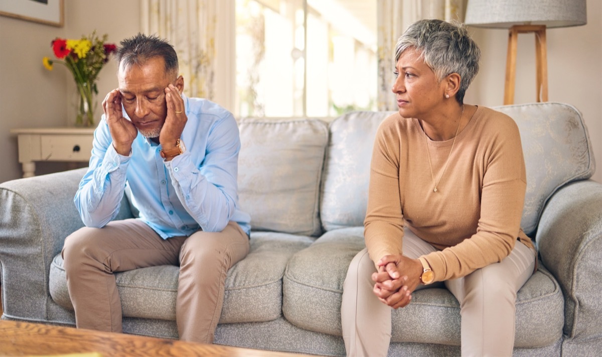 mature couple sitting on couch looking upset at each other