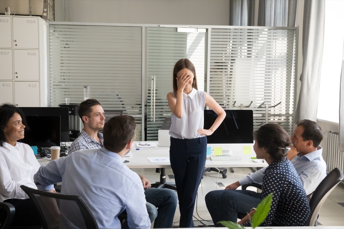 nervous bashful female employee feels embarrassed blushing afraid of public speaking at corporate group team meeting