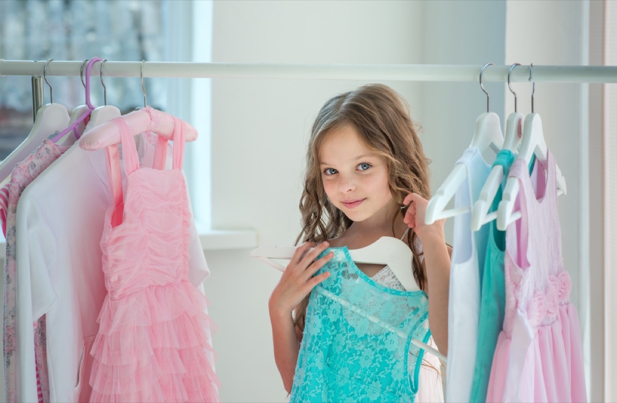 little girl in closet holding dress in closet, parenting tips