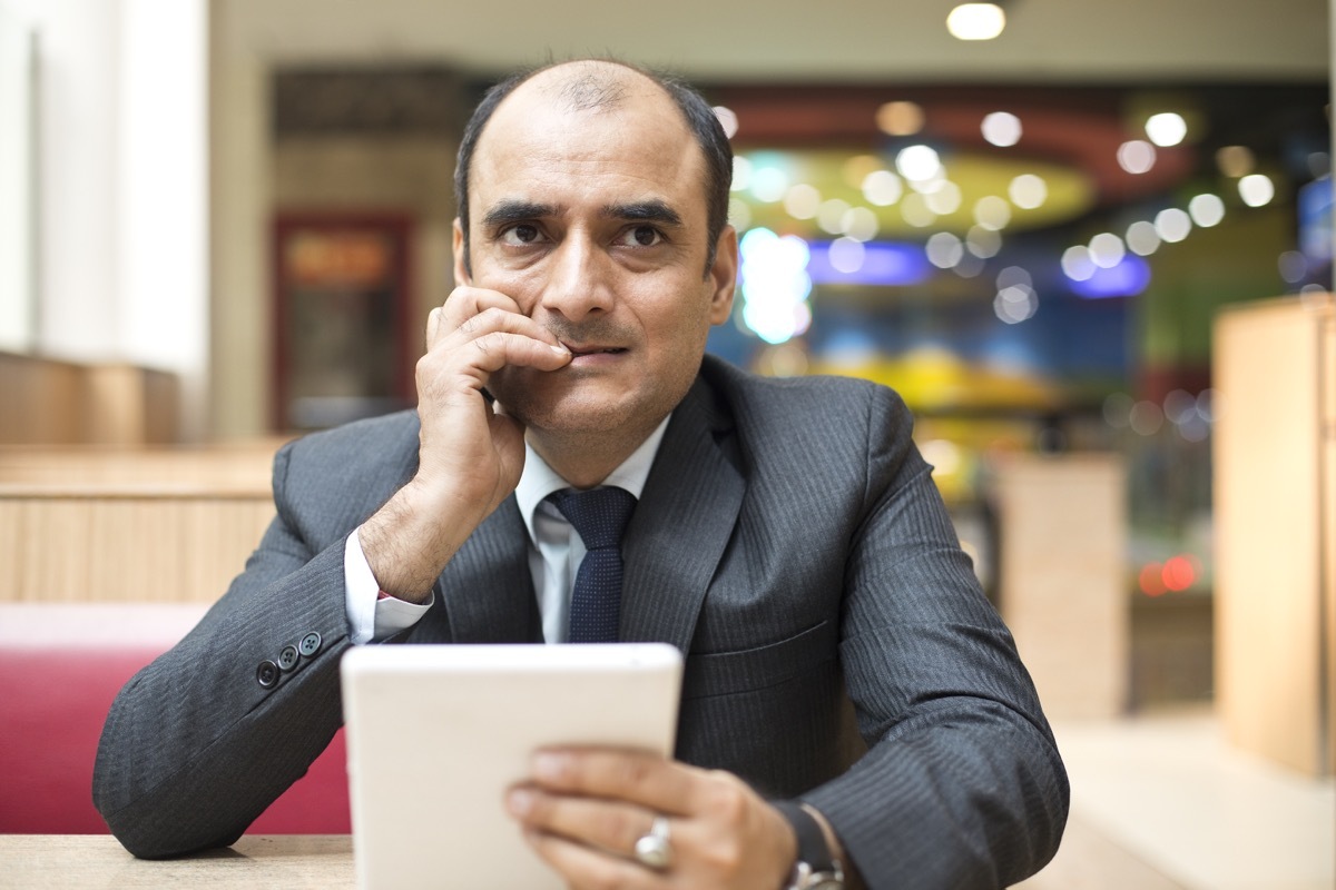 Serious businessman using digital tablet at cafe