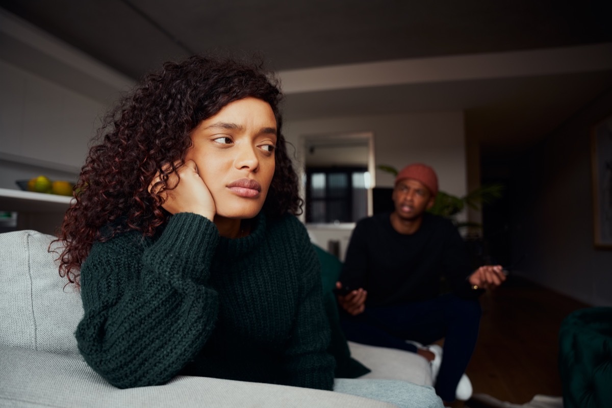 Couple arguing in their apartment, woman looks upset. 