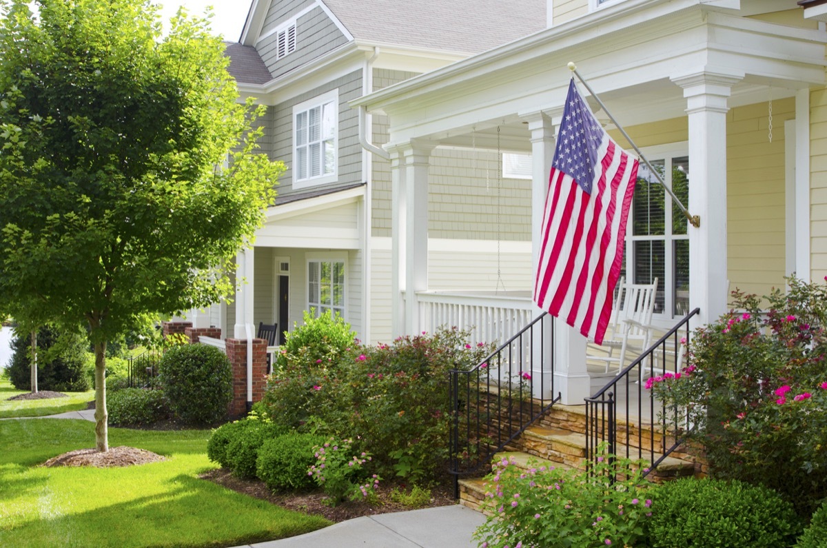 Detail of a bungalow/cottage-style front porch with an American Flag hanging from the front column.