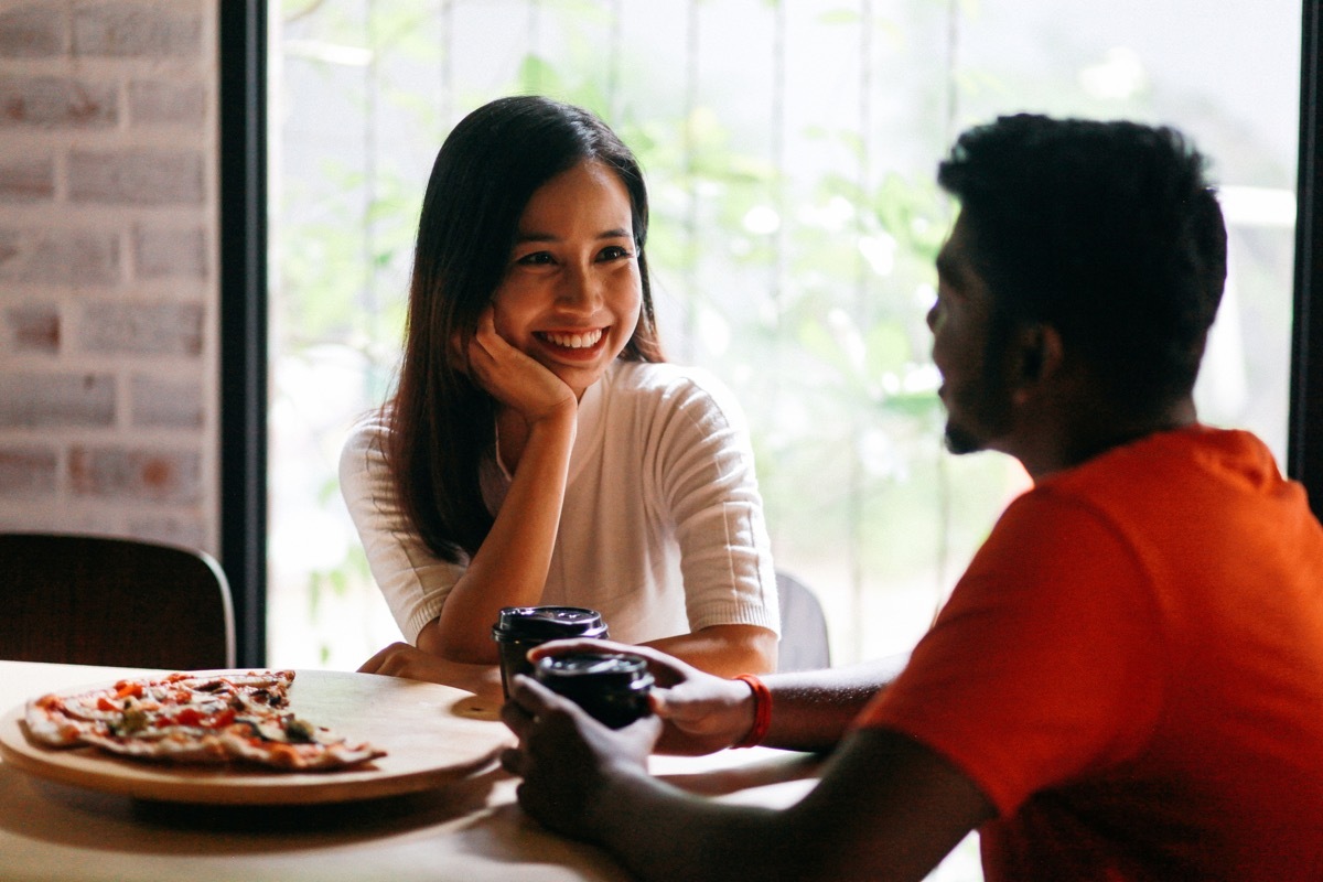 young couple sitting at a dinner table with their elbows on table