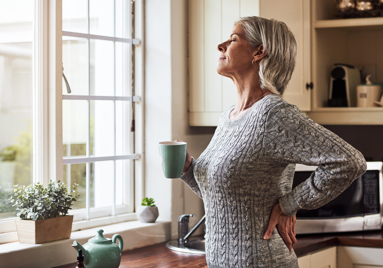 Woman holding a mug and looking out the window.