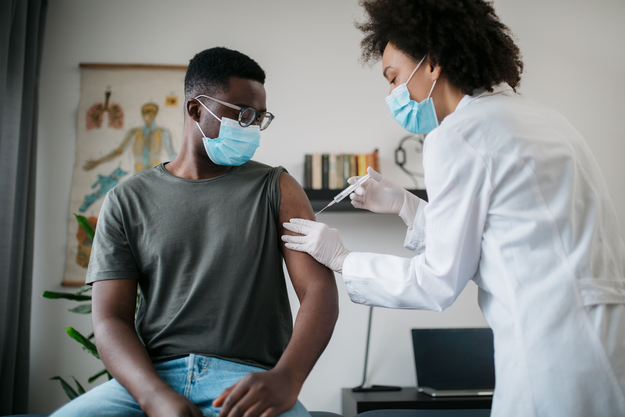 A young man receives a COVID vaccine from a healthcare worker