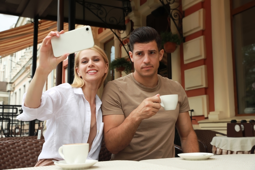 Young unhappy couple trying to take selfie